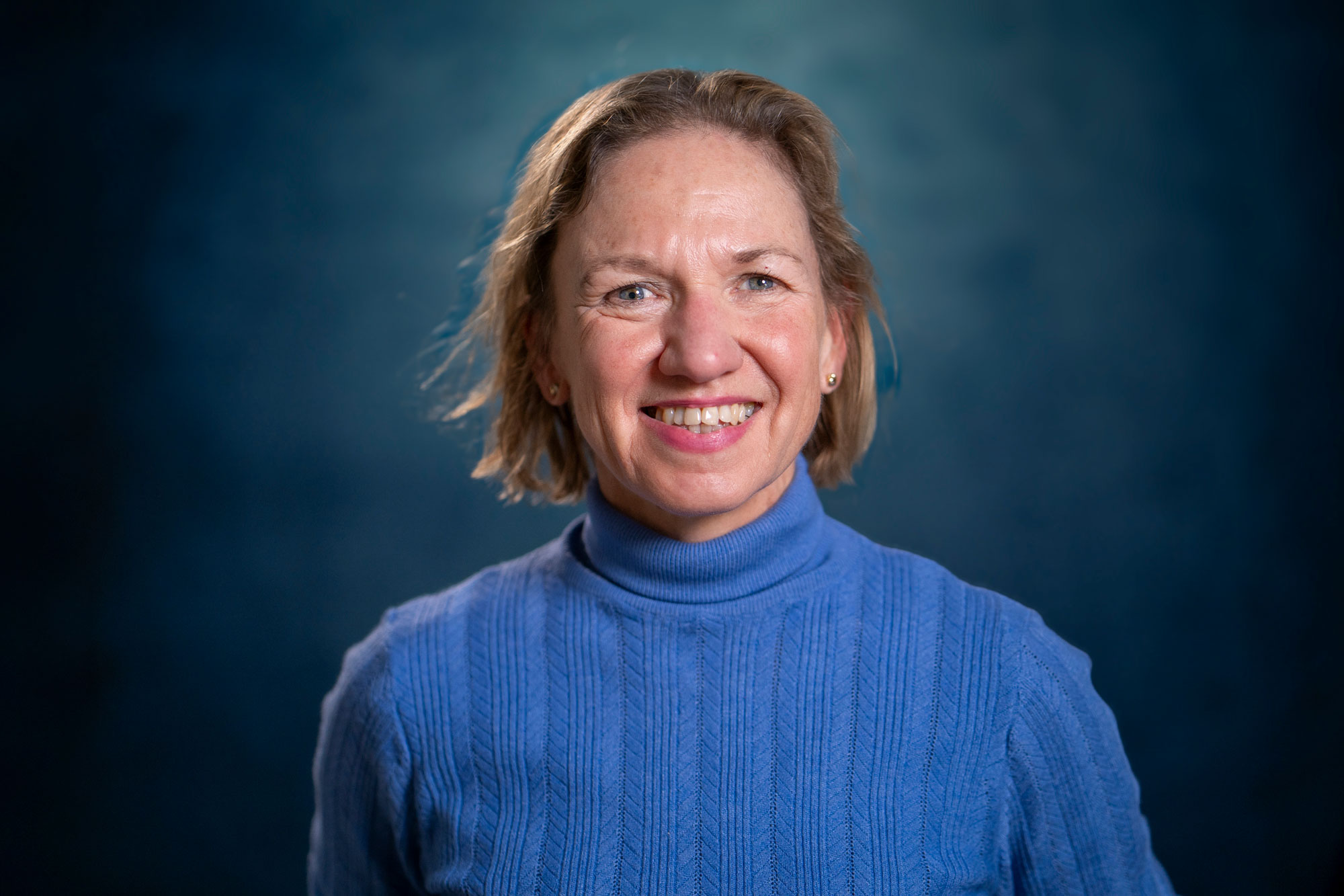 Je ziet een witte vrouw met een blauwe trui op een blauwe achtergrond